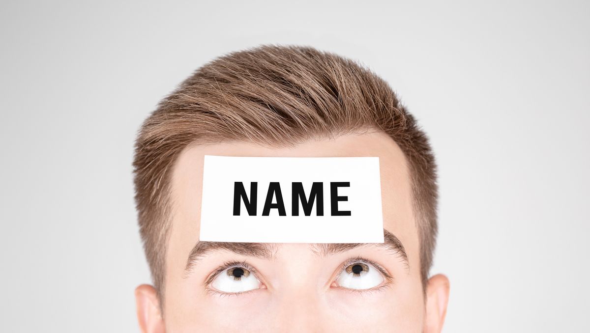 Man,Looking,At,Paper,With,Word,Name,Pasted,On,His